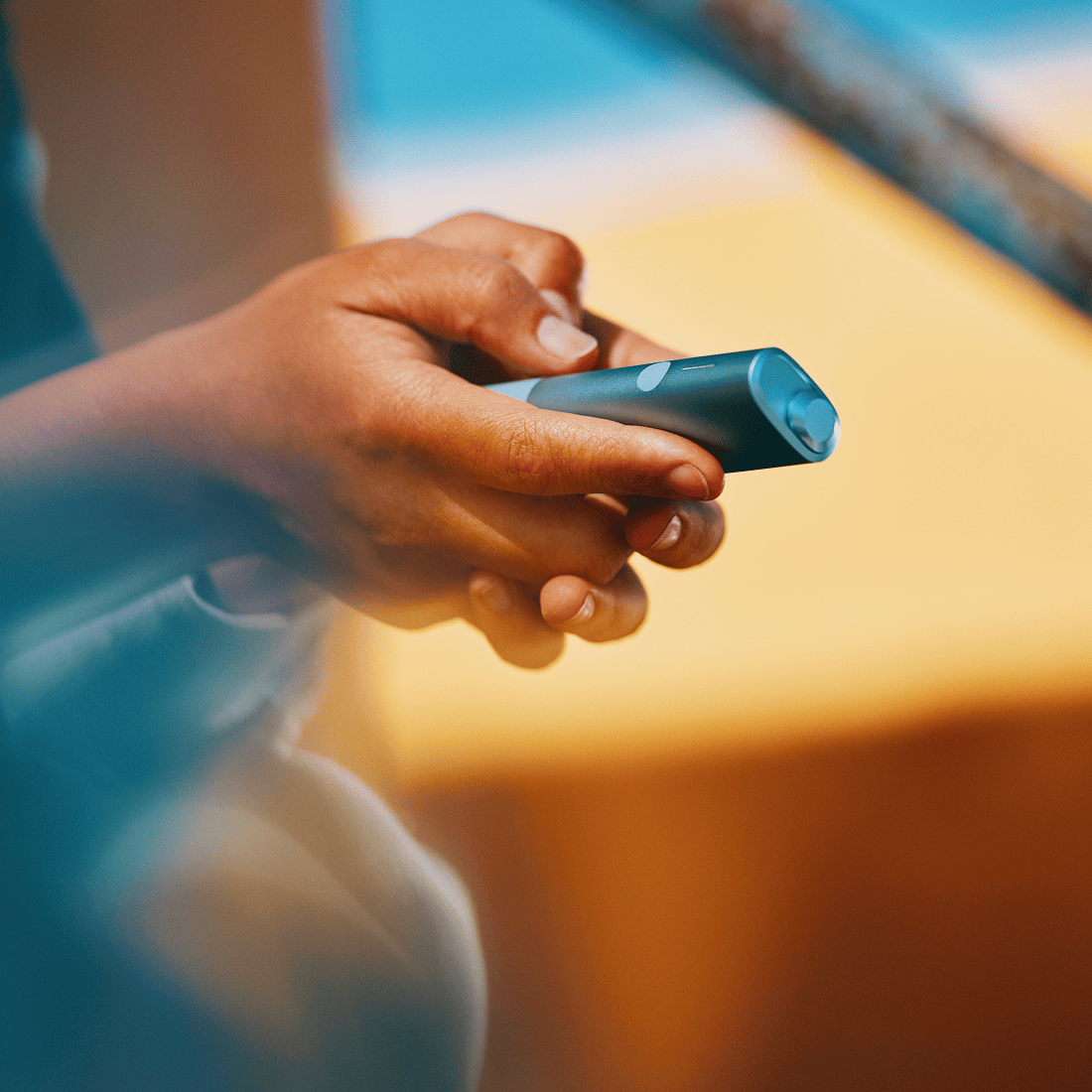 A person holding an IQOS ILUMA i ONE color Breeze Blue with their hands